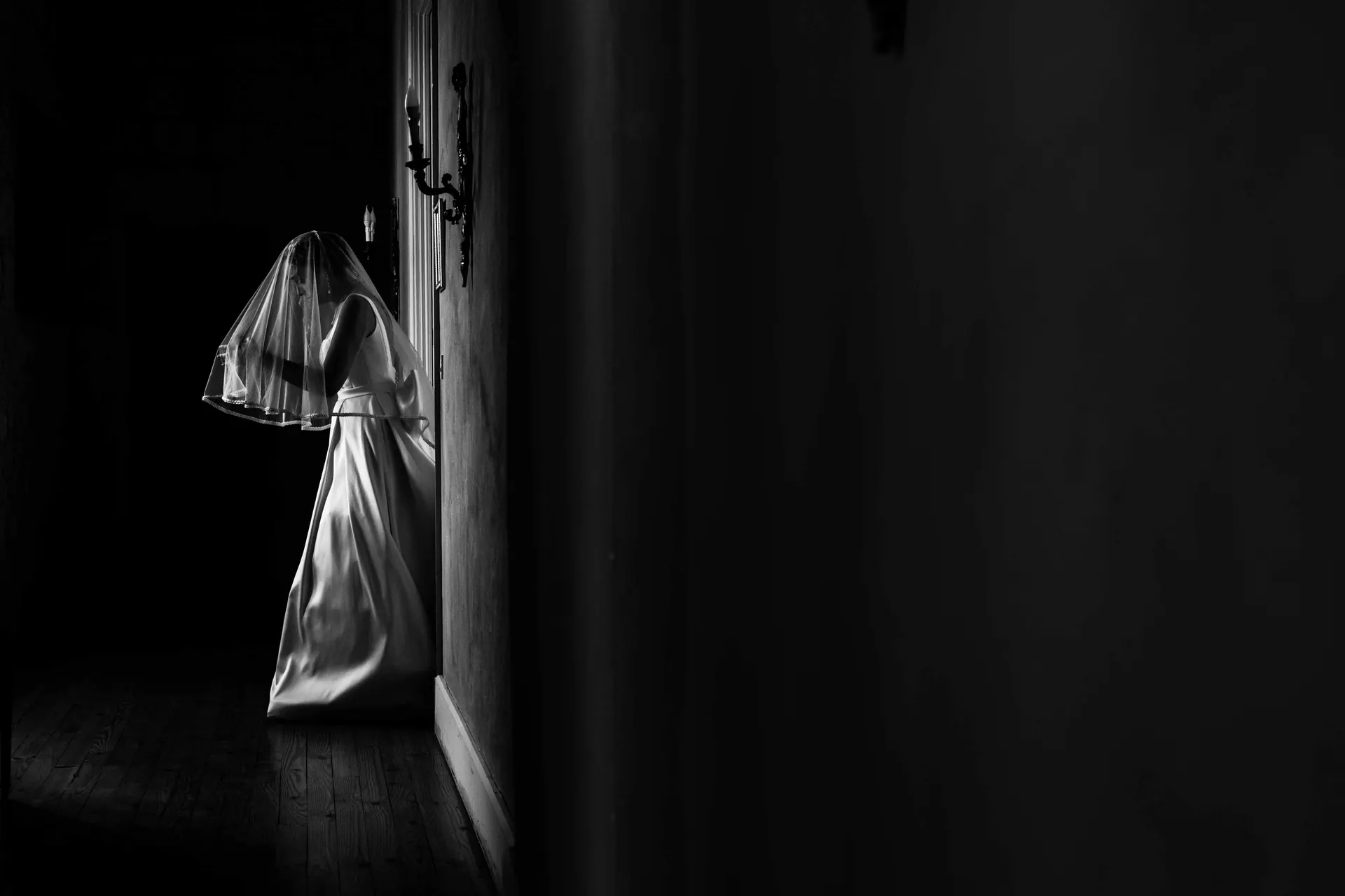 Mariée sous son voile dans un couloir sombre, en clair-obscur